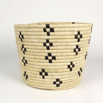 A handwoven bin in tan with a  flower geometric pattern in black