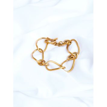 Flatlay of a brass Orma bracelet on a white sheet