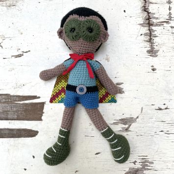 Flatlay of a Rafiki Wema Superhero Boy doll wearing a multi colored outfit