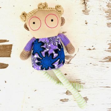 Flatlay of a Wiz Buddie doll wearing a multi colored outfit