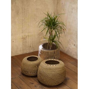 Three woven baskets on a wooden floor with a plant in one.