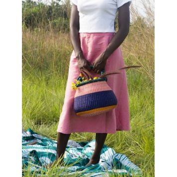 Front view of model holding a pink and blue Bolo Colour Block Basket with green handle and orange bottom