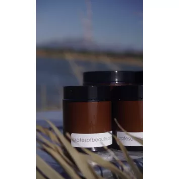 Front view of three amber glass candle jars closed with black lids