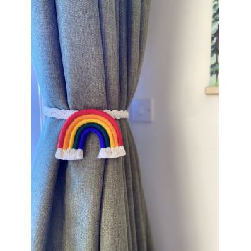 A rainbow colored curtain tie wrapped around a gray curtain