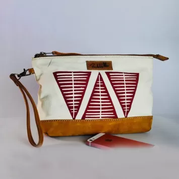White handmade clutch bag with red and white geometric on the front and tan leather wristlet