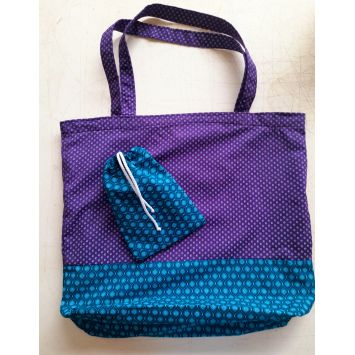 Purple shweshwe fabric bag with blue shweshwe fabric at the bottom  of the the bag and a blue shweshwe fabric pouch with a string on top of it