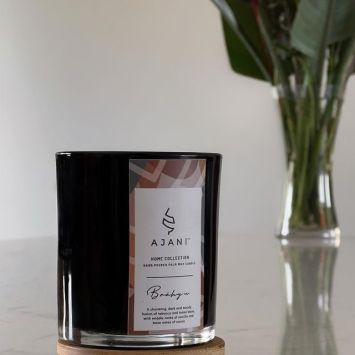Ajani Brähyu Scented Candle
in front of a vase with flower stems