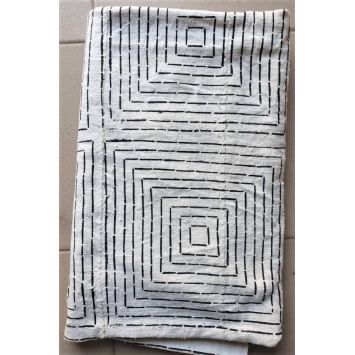 Flatlay of a folded, white Bogolan Mudcloth with black patterns