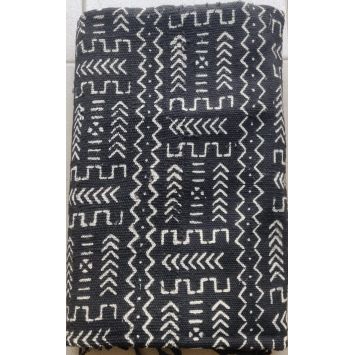Flatlay of a folded, black Bogolan Mudcloth with white patterns