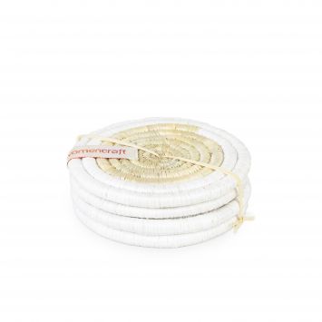 Four white and natural tan round grass woven coasters stacked on top of each other bound together with a natural tan string