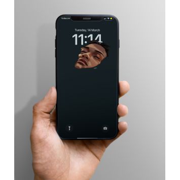 A phone being held out. The lockscreen is partial face of a person in a dark gray background