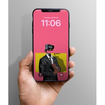 A phone being held out. The lockscreen has a pink background showing a person wearing a suit and standing in front of a yellow background with their head replaced by a camera