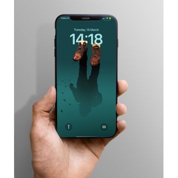 A hand holding a phone which presents a lock screen showing a shadow of a person under brown shoes in a blue background