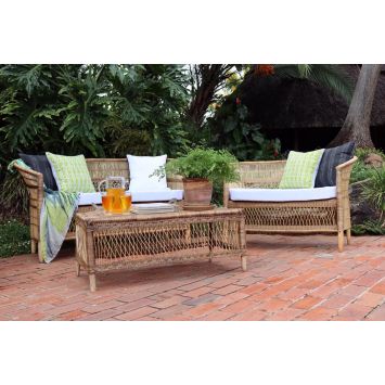 Double cane chairs placed next to a table with several pillows on them