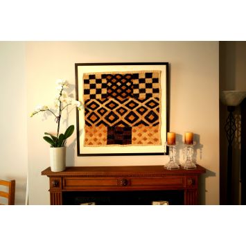 Front view of a multi-pattern, multi-colored Kuba Duarra textile, framed and hanging on a wall
