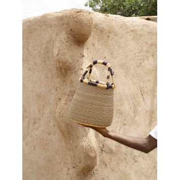 Front view of model holding a tan and indigo Bowl Black/Natural Stripe Basket next to a wall