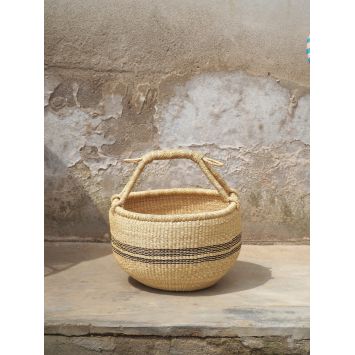 Front view of a tan Kilika Stripe basket with black designs next to a wall