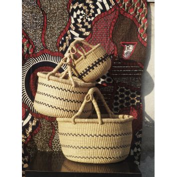 Three tan Kilika Check Check Baskets with black deigns stacked on top of each other next to a multi-colored fabric