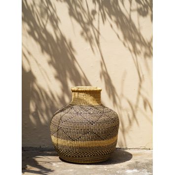 Front view of a black and tan flower pot basket next to a wall