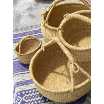 Top view of tan Kilika Natural baskets in assorted sizes on top of a tan and purple mat