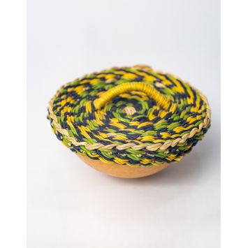 A top view of multi-colored elephant grass cover (in yellow, green, and blue) which is covering a calabash.
